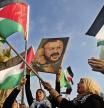 FILE - Palestinian women shout slogans while waving their national flags with a picture of jailed leader Marwan Barghouti, during a protest in Beirut, Lebanon, on May 4, 2017. Hamas officials say that any cease-fire deal with Israel should include the release of prisoner Marwan Barghouti — a leader of the militant group's main political rival. The demand by Hamas marks the central role Barghouti plays in Palestinian politics — even after more than two decades behind bars and sentenced by Israel to multiple life terms in prison. (AP Photo/Hussein Malla, File)