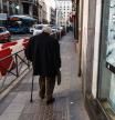 Jubilado por calle de madrid con cartel de Publicidad sobre pensionistas