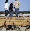 Una familia contempla el océano Pacífico desde el lugar donde se levantaba su casa, arrasada por el tsunami del pasado 24 de abril.