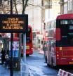 Un típico autobús londinense de dos plantas pasa junto a un cartel en el que se anuncia el alto riesgo de contagio y se pide a los ciudadanos que tomen precauciones ante la expansión del coronavirus