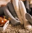 Lower section of three unrecognizable young girlfriends sitting on the bedroom floor in their cozy socks and hanging out together while enjoying some warm tea on a cold autumn day.