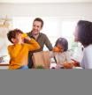 Family Returning Home From Shopping Trip Using Plastic Free Bags Unpacking Groceries In Kitchen