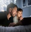 Shot of a father and his little son using a digital tablet together in bed at night