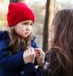 Scared daughter holding mother's hands in autumn park. Child girl express sad emotions, complain about their own problems