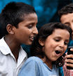 Dos niños y una niña observando un teléfono móvil