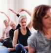 Group of active senior people doing yoga exercise in community center club.