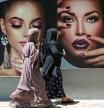 Burqa clad women walk past a billboard put up on the wall of a beauty salon in Kabul on August 7, 2021. (Photo by SAJJAD HUSSAIN / AFP)