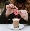 Una mujer echa sacarina a su café