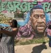 FILE - In this Tuesday, April 20, 2021, file photo, Laynette Jacob takes a photo in front of a George Floyd mural with her friends near the intersection of Elgin and Ennis as she joins others as they react after learning of the guilty verdict on all counts in the murder trial of former Minneapolis police Officer Derek Chauvin in the death of George Floyd, in Houston. In an announcement Monday, Oct. 4, 2021, a Texas agency has approved a request that Floyd be granted a posthumous pardon for a 2004 drug arrest made by a now indicted ex-Houston police officer whose case history is under scrutiny following a deadly drug raid. (Brett Coomer/Houston Chronicle via AP, File)
