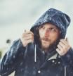 Hombre con chubasquero protegiéndose de la lluvia.