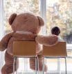 Watching autumn rain. Little boy sitting with his big soft teddy bear friend on chairs ion front of window looking outside. Fall lifestyle. Frendship. Seasonal mood