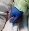 FILE PHOTO: A woman in her personal protective equipment (PPE) gear holds the hand of a coronavirus disease (COVID-19) positive patient, in her isolation room at Madison Memorial Hospital in Rexburg, Idaho, U.S., October 28, 2021. Picture taken October 28, 2021. REUTERS/Shannon Stapleton/File Photo