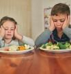 Cropped shot of two grumpy children refusing to eat their vegetables