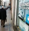 Jubilado por calle de madrid con cartel de Publicidad sobre pensionistas