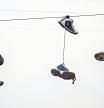 Tres pares de zapatillas cuelgan de un cable en la calle