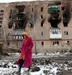A woman walks in front of a residential building which was damaged during Ukraine-Russia conflict in the separatist-controlled town of Volnovakha in the Donetsk region, Ukraine March 11, 2022. REUTERS/Alexander Ermochenko