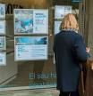Una mujer mira las ofertas de compra, venta, alquiler de vivendas en un escaparate de una inmobiliaria