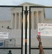 FILE - A demonstrator places a sign on the anti-scaling fence outside of the U.S. Supreme Court, Thursday, May 5, 2022 in Washington. As the United States Supreme Court appears poised to overturn Roe v. Wade, Muslim Americans are gearing up for what the landmark reversal could mean for their communities. (AP Photo/Alex Brandon, File)