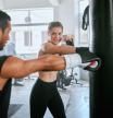 Serious and fit man and woman looking active, fit and sporty while training together for fitness at the gym. Young couple boxing, exercising and doing a routine cardio workout at a sports center