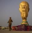 Un hombre junto a una réplica de la Copa del Mundo ante el estadio Lusail