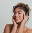 Portrait of a beautiful young woman with curly hair without make-up, studio shot in front of white background