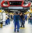 Employees work on the chassis assembly of automobiles as they pass along an overhead conveyor belt at the Ford Motor Co. plant in Almusafes, Spain, on Monday, April 18, 2016. Ford's Valencia plant is one of the most advanced, flexible and productive auto plants in the world according to a company statement. Photographer: Pau Barrena/Bloomberg