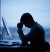 Tired or stressed businessman sitting in front of computer in office