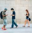 A small group of people playing a game on their smart phones and walking around the city.