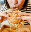 Woman eating a hamburger in modern fastfood cafe, lunch concept
