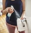 Woman cleaning a door handle with a disinfection spray and disposable wipe. Woman sanitizing door handle with antibacterial spray. Girl staying at home during coronavirus outbreak