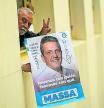 A worker of the Economy Ministry holds an electoral propaganda poster of the Argentine Economy Minister and presidential candidate for the Union por la Patria party, Sergio Massa, while waiting for his arrival to hold a press conference with the foreign press in Buenos Aires on October 23, 2023, a day after winning the first round of the presidential election. Argentina's Economy Minister Sergio Massa and anti-establishment outsider Javier Milei will face off in a runoff presidential poll, a battle between two wildly different versions of the country, election results showed Sunday. (Photo by JUAN MABROMATA / AFP)