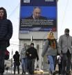 People walk past an electronic billboard on a building showing Russian President Vladimir Putin as he gives his annual state-of-the-nation address in Moscow, Russia, on Thursday, Feb. 29, 2024. (AP Photo/Dmitry Serebryakov)