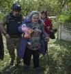 Volunteer Vitaliy Kylchik helps Valentyna to walk to a car during evacuation to Kharkiv, in Vovchansk, Ukraine, on Saturday, May 11, 2024. (AP Photo/Evgeniy Maloletka)