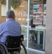 Una persona con discapacidad delante de una inmobiliaria de Girona.