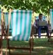 A man works on his laptop from a deck chair in St James's Park during a heatwave, in London, Britain, August 12, 2025. REUTERS/Jack Taylor