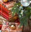 Christmas gifts wrapped in paper and an archive of old books under a decorated Christmas tree. Postcard.