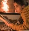 Una chica disfruta del placer de la lectura junto al fuego en invierno