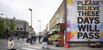 LONDON,  ENGLAND - APRIL 25: A woman in face mask walks past a poster stating 'Please beleive these days will pass' in East London on April 25, 2020 in London, England. The British government has extended the lockdown restrictions first introduced on March 23 that are meant to slow the spread of COVID-19. (Photo by Justin Setterfield/Getty Images)
