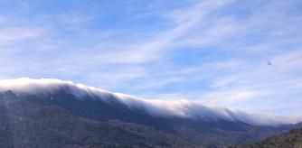 La montaña cubierta en su parte superior por la niebla caída hace que en su conjunto parezca una ola gigante.