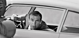 Connery, al volante del mítico Aston Martin, atiende las instrucciones del director de ‘Goldfinger’, el británico Guy Hamilton