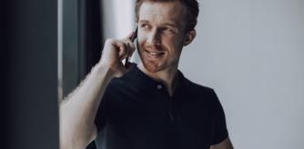 Hombre hablando por teléfono con polo oscuro.