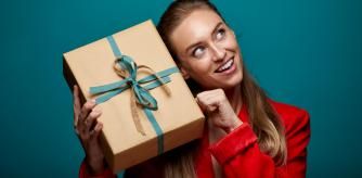 Mujer sosteniendo un regalo de Navidad tratando de averiguar qué es