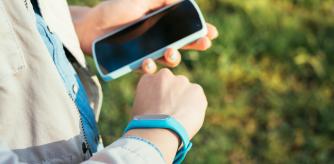 La mujer revisa los datos de la pulsera de actividad en un teléfono móvil