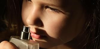 Niña huele colonia de una botella