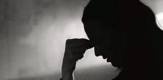 Young woman feeling sad in a dark setting.