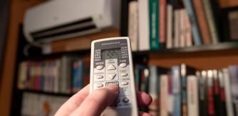 Una persona regula la temperatura del aire acondicionado en casa