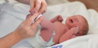 a Paediatrician administers a heel prick test to check sucrose levels in a newborn baby boy after a caesarean section.