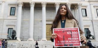 Ángela Sánchez Pérez Merino, docente de la comunidad de Madrid, posa frente al Congreso de los Diputados para presentar la lista de firmas recogidas para una campaña de regulación de los teléfonos móviles en menores, que ha organizado junto a otra decente de secundaria, este jueves en Madrid