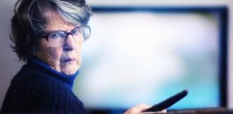 Mujer con cara de disgusto al ver que su televisor está obsoleto y no puede ver los canales de la  TDT HD