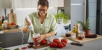 Una mujer cocinando con una batidora de mano.